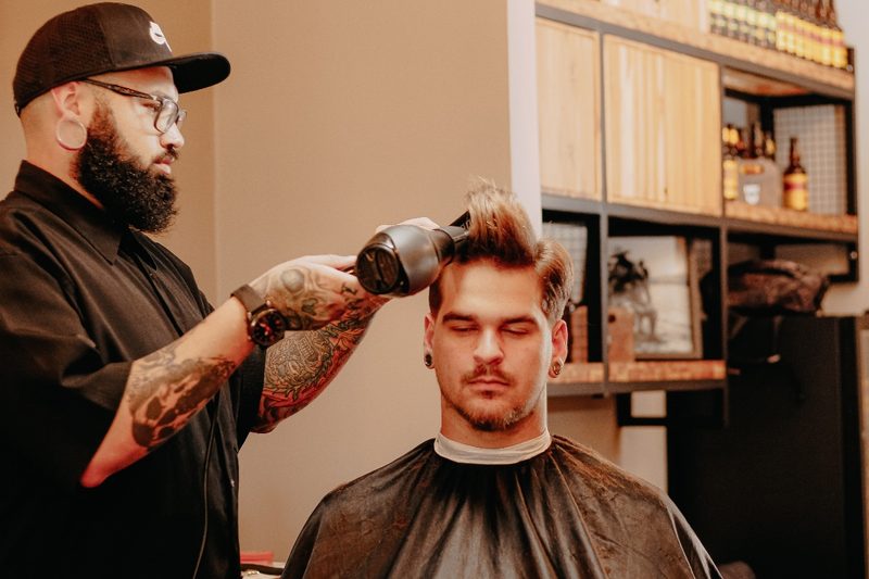 a man blow drying his hair at barber shop