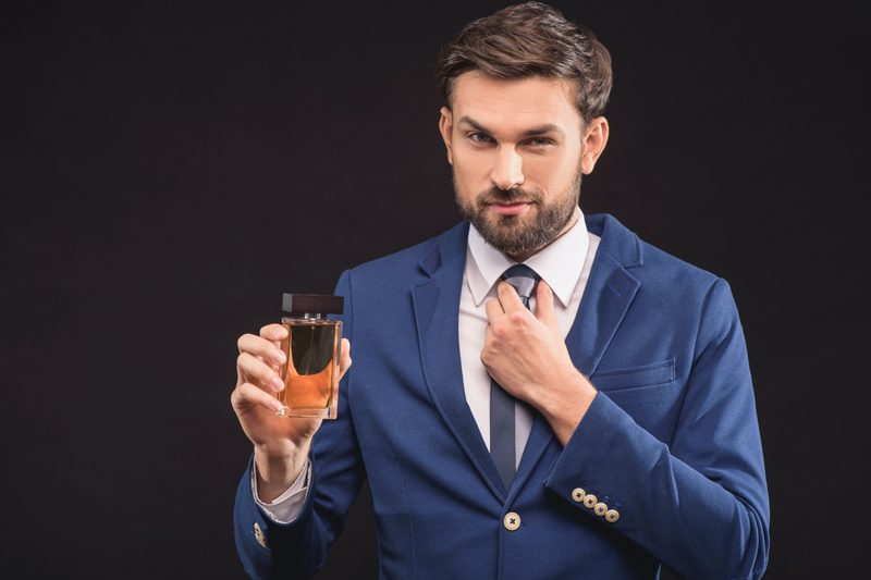Man holding a bottle of fragrance.