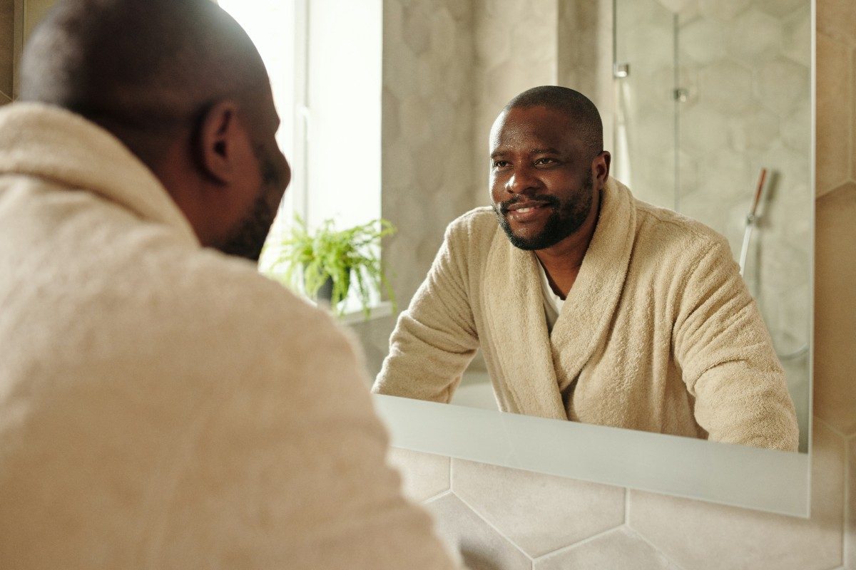 man in bathrobe smiling in the mirror