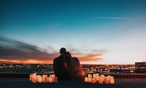 A couple on a romantic date outside with candles surrounding them.