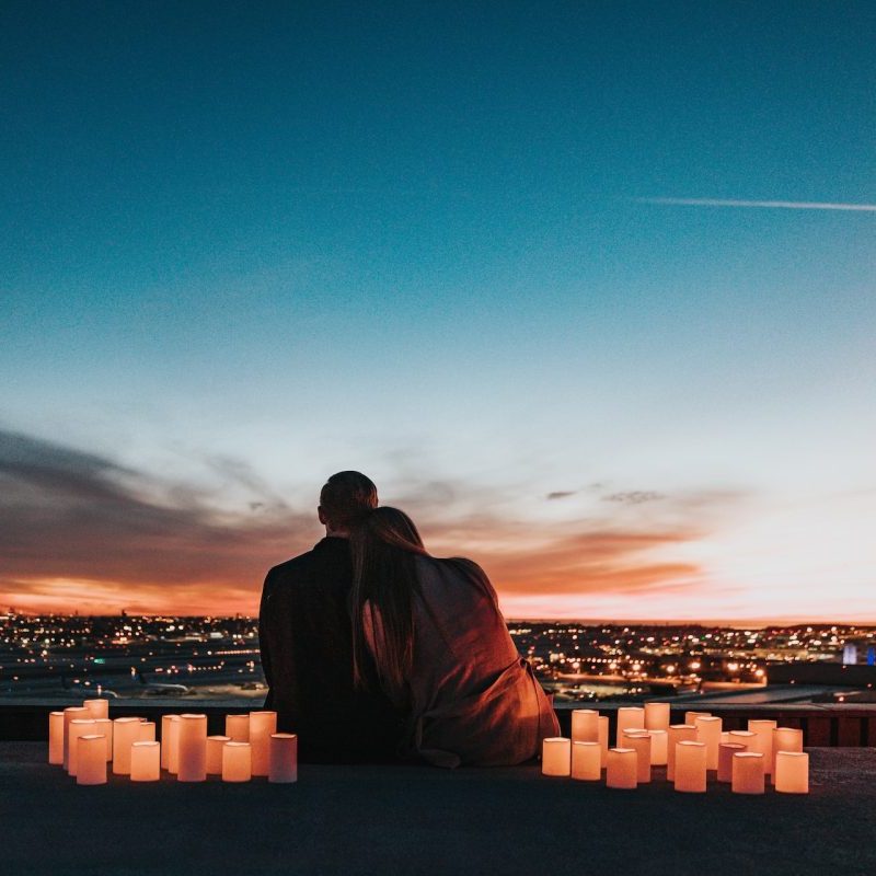 A couple on a romantic date outside with candles surrounding them.