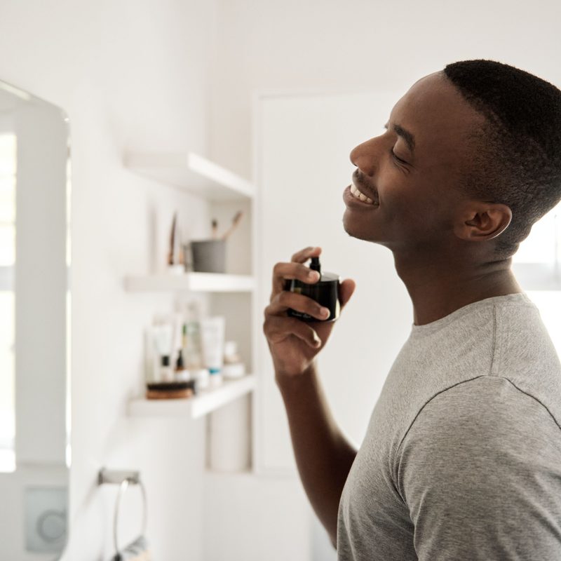 Person spraying cologne on their neck
