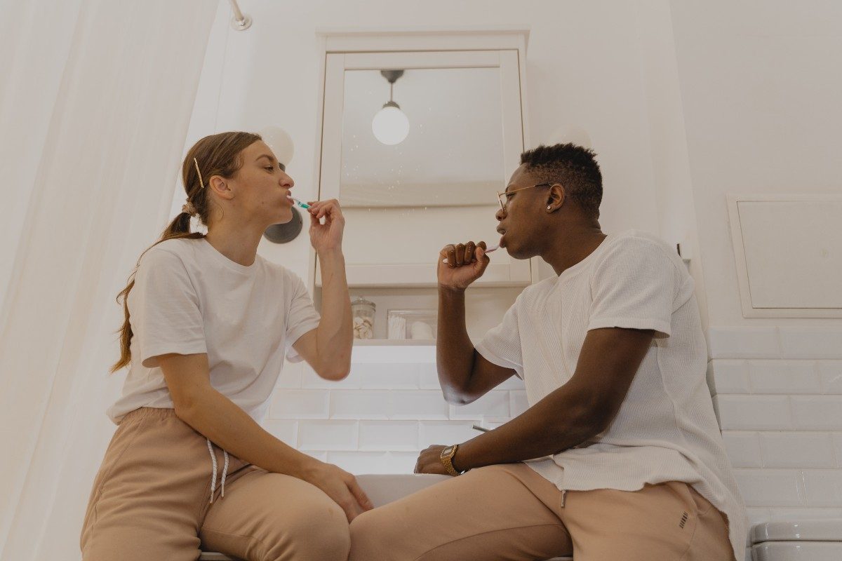 two people brushing their teeth in a bathroom
