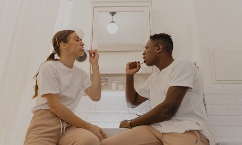 two people brushing their teeth in a bathroom