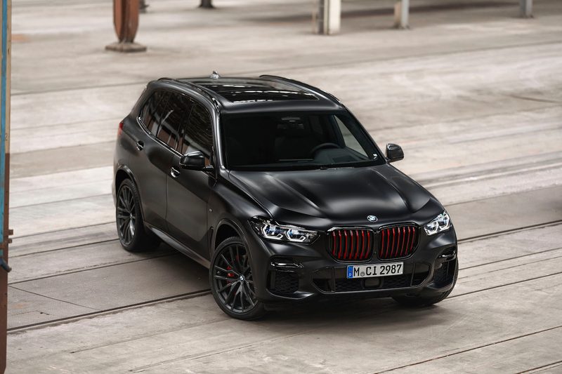 2022 BMW X5 Black Vermilion Edition front end angle from passenger's side parked in a warehouse.