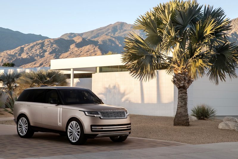 2022 Land Rover Range Rover front end angle from passenger's side in front of a mansion and a palm tree with mountains in the back.