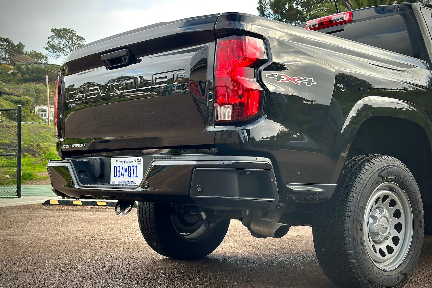 Rear end close up of the 2023 Chevrolet Colorado with taillight and rear tailgate with trees in the back.