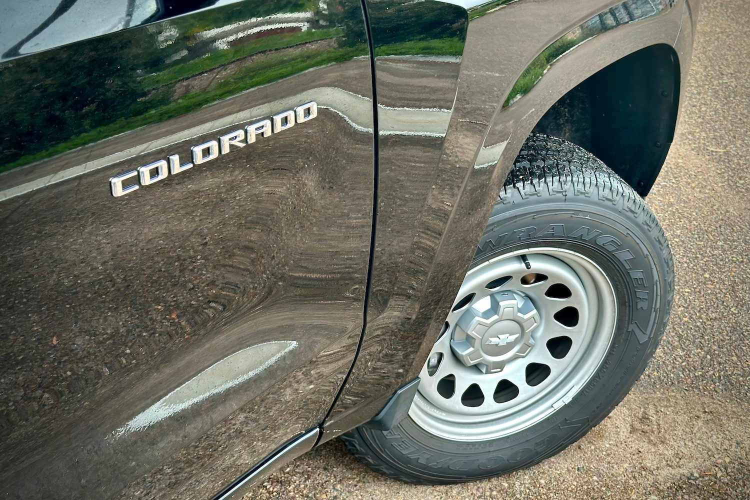 Angle of the front wheel on the 2023 Chevrolet Colorado and badge parked on a gravel road.