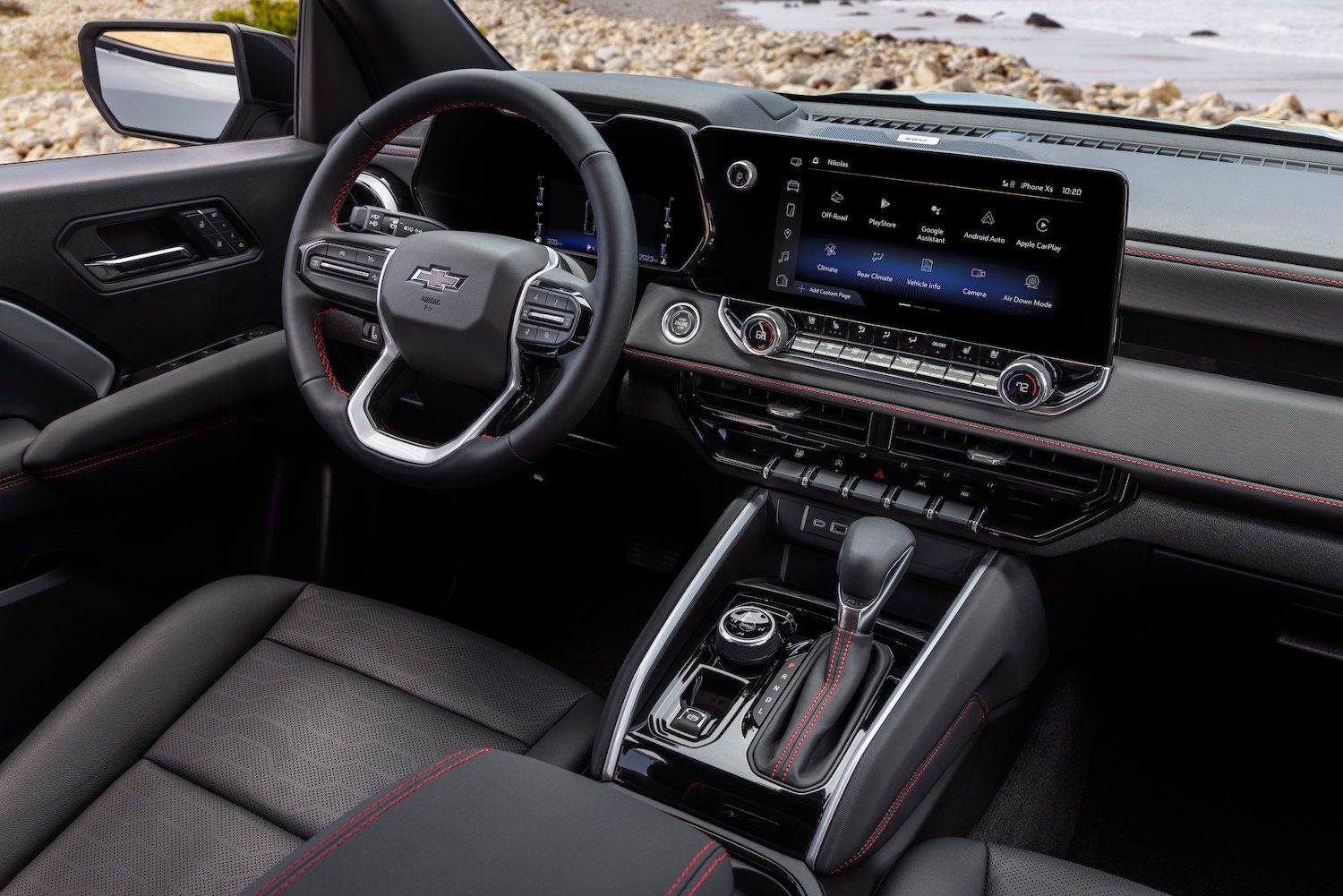 Close up of the steering wheel and dashboard in the 2023 Chevrolet Colorado Z71 trim with the ocean in the back.
