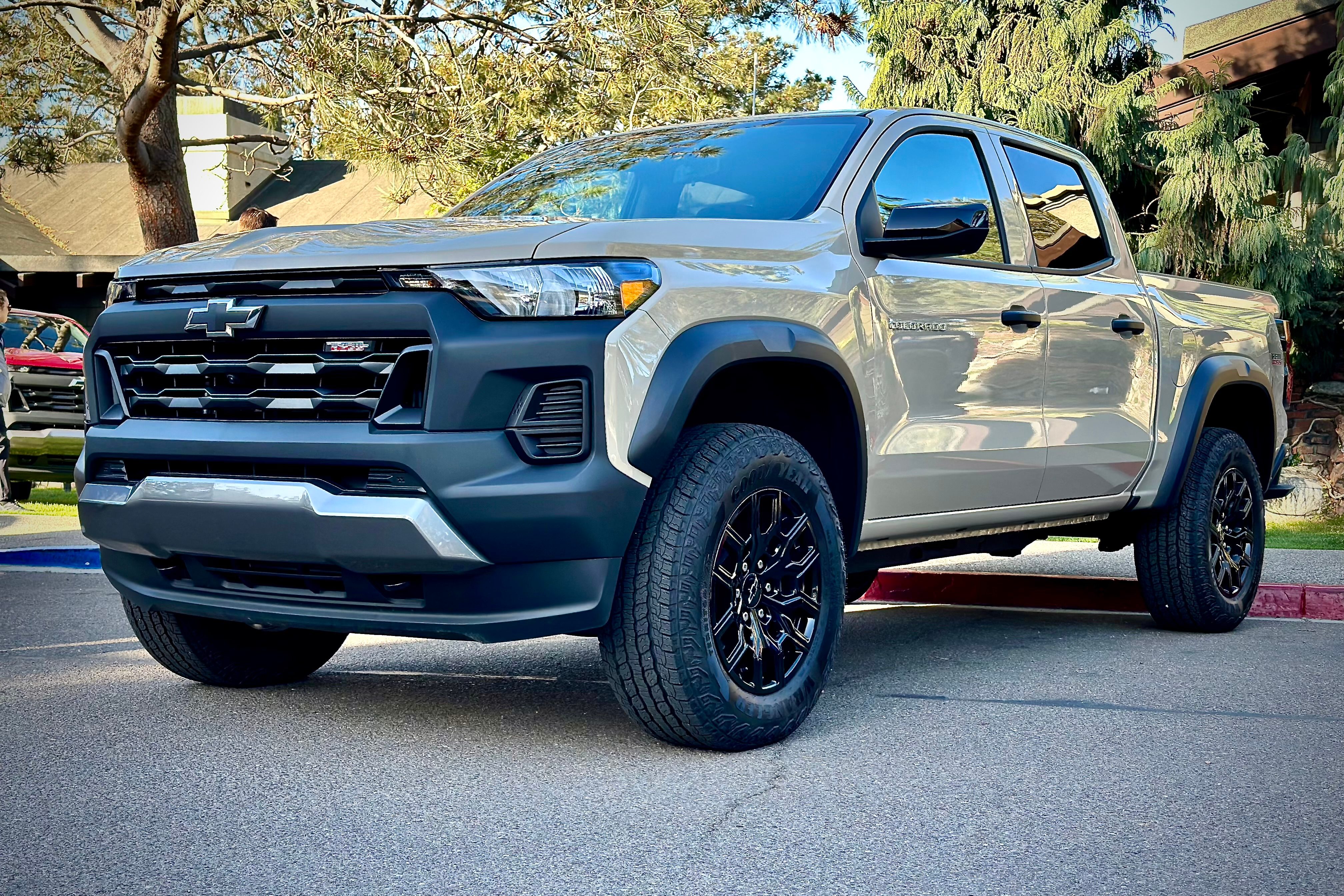 2023 Chevrolet Colorado Trail Boss front end angle parked in front of a lodge with trees.