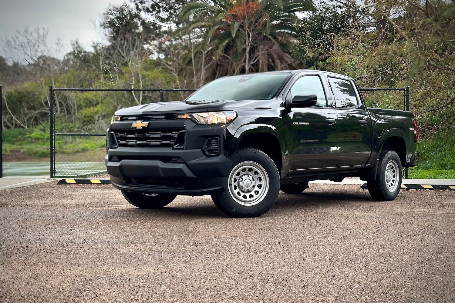Front end angle of the 2023 Chevrolet Colorado WT from the driver's side parked in front of a tennis court.