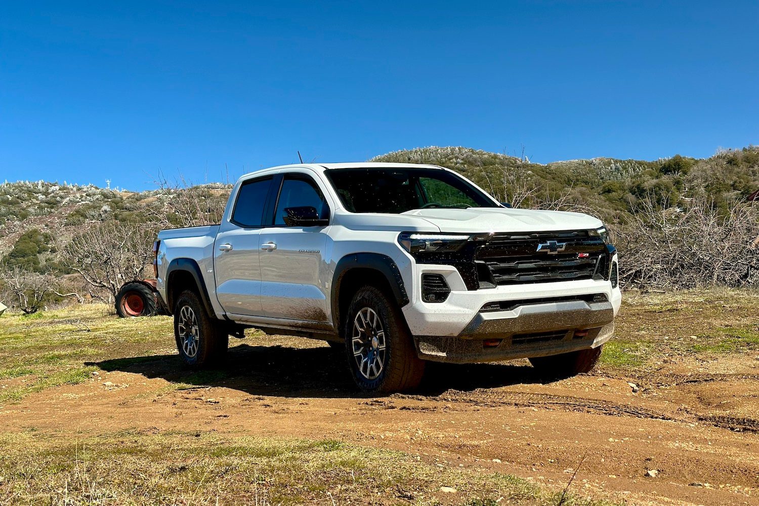 Front end angle of the 2023 Chevrolet Colorado Z71 from driver's side parked in a muddy field.