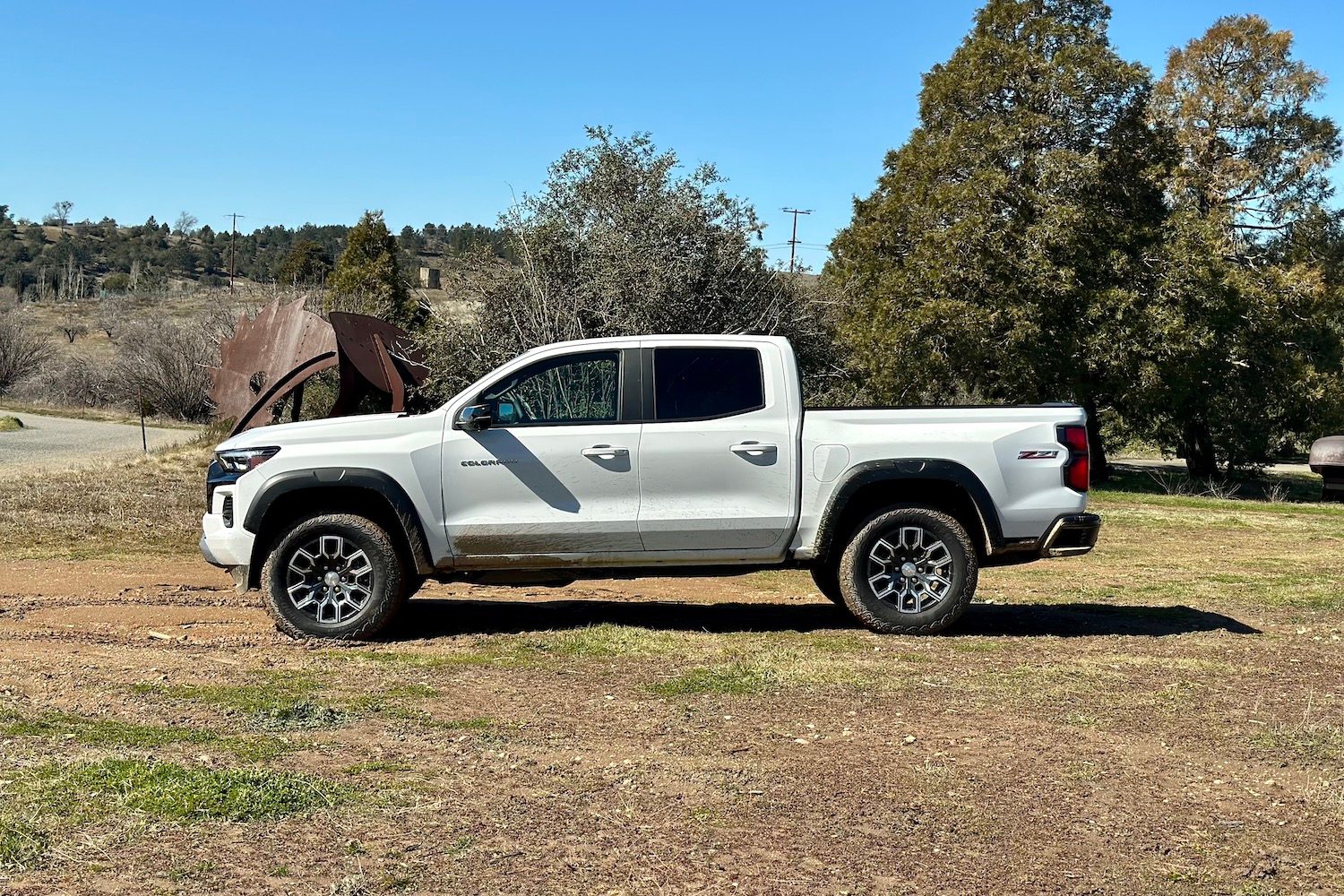 Side profile of the 2023 Chevrolet Colorado Z71 parked in a muddy field with trees in the back.