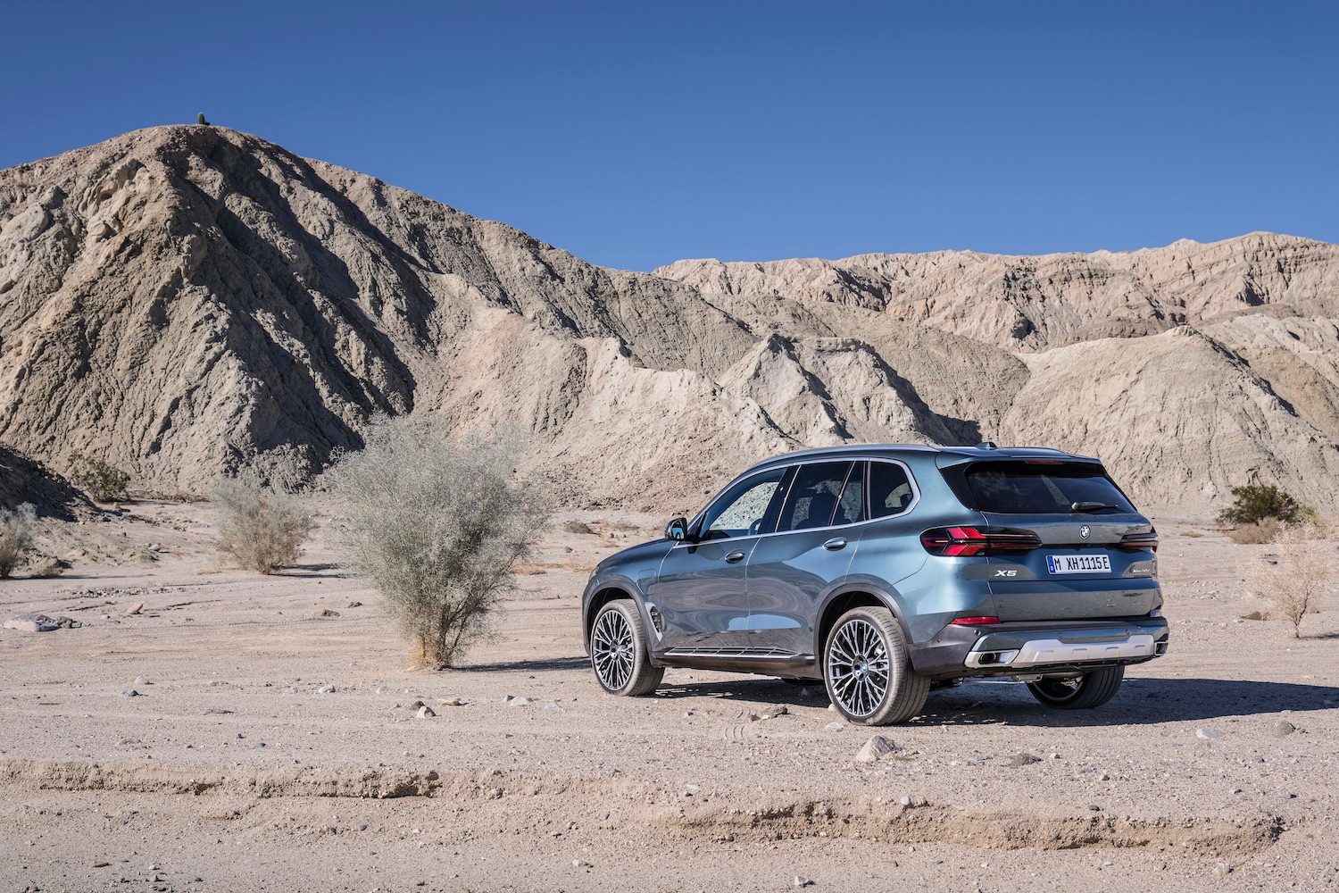 2024 BMW X5 rear and angle from driver's side parked in front of a mountain.