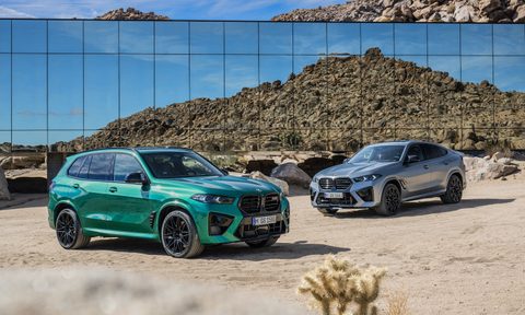 2024 BMW X5 M and X6 M Competition parked in front of a glass building in the desert with mountains in the back.