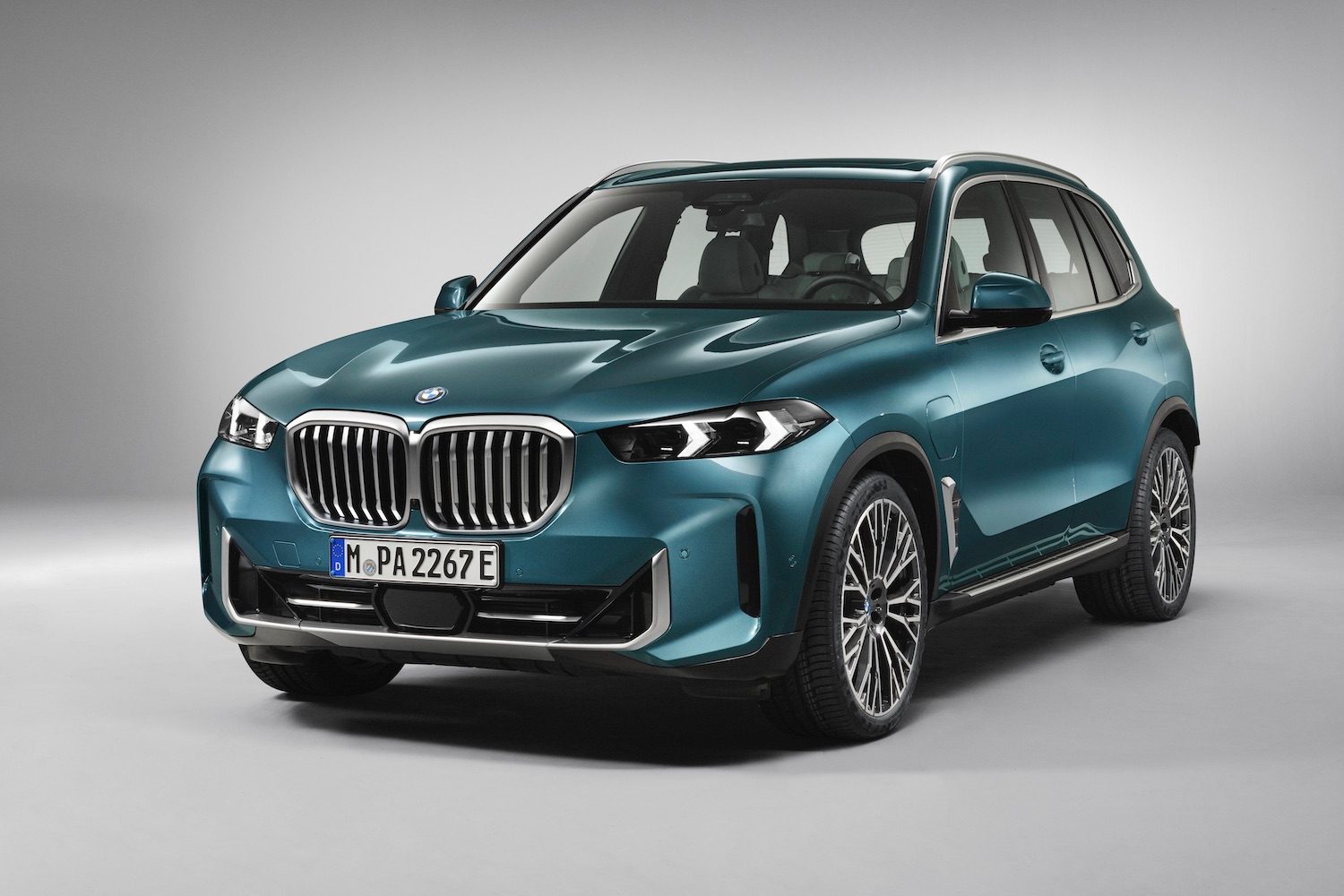 front end angle of 2024 BMW X5 xDrive50e PHEV parked in a white studio.