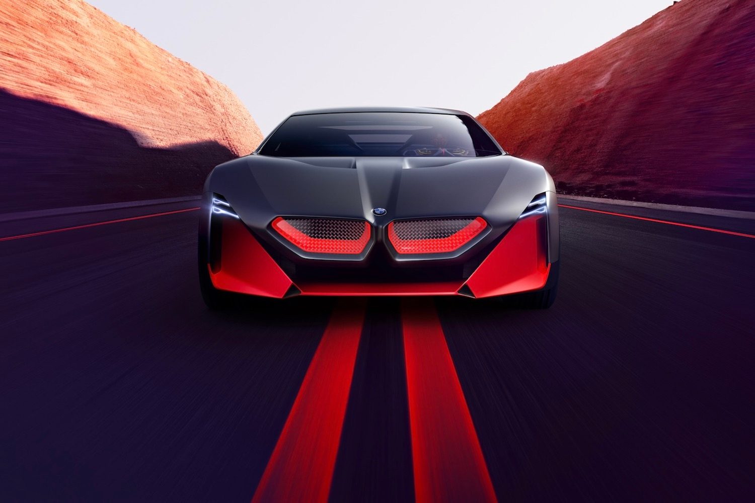 Close up of the front end of BMW M Vision NEXT Concept driving down the road with mountains in the back.