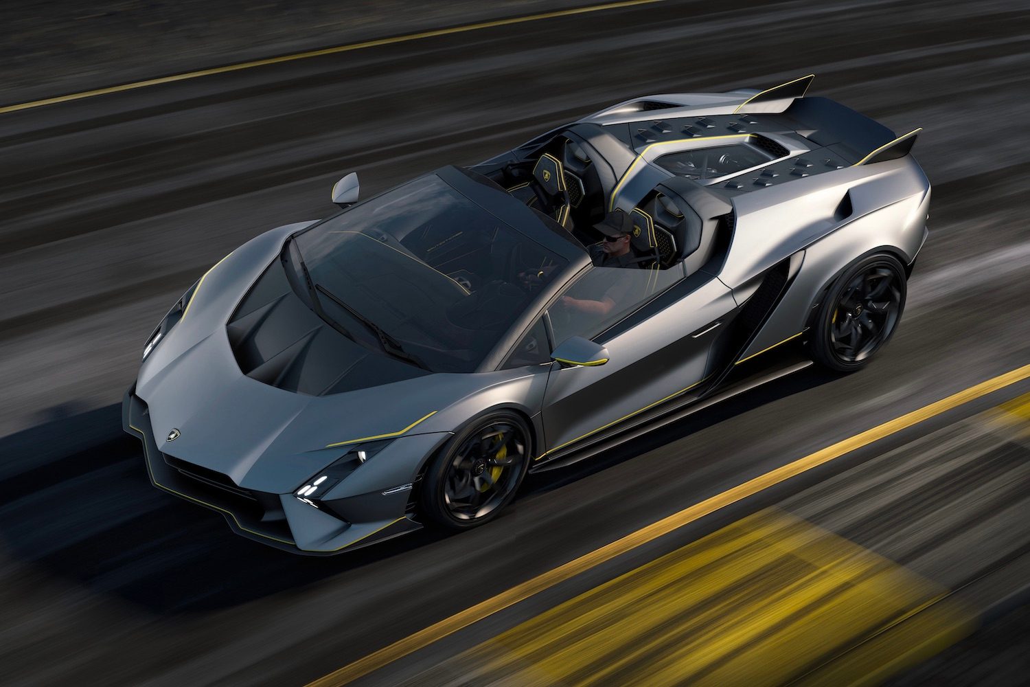 Lamborghini Aut&eacute;ntica overhead front end shot from driver's side with a driver driving down a windy road.