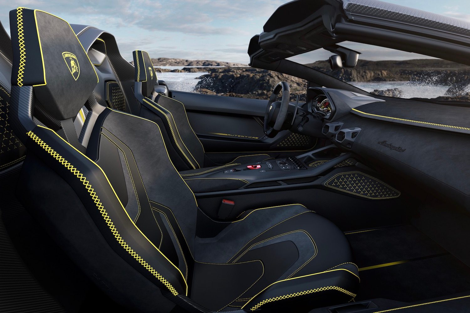 Front seats in the Lamborghini Aut&eacute;ntica from the passenger side outside the car with cliffs and water in the back.