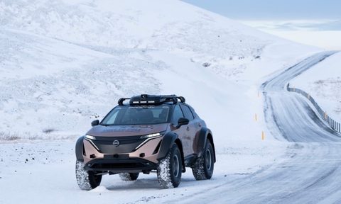 Front end of Nissan Ariya angle from driver's side parked on the side of an icy road in front of snowy mountains.