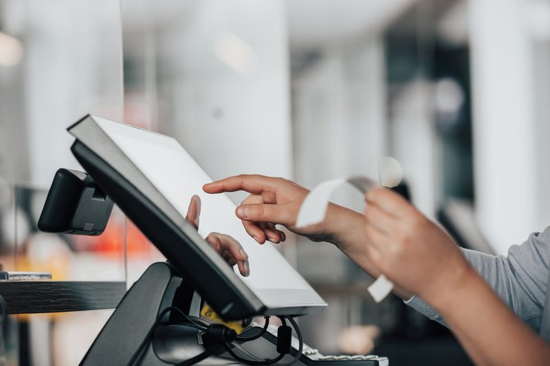 Clerk tapping touchscreen register while holding a receipt.