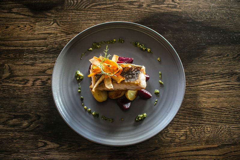 Gourmet sea bass served on a dark plate.