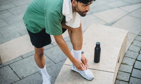 Man tying his sneakers outside
