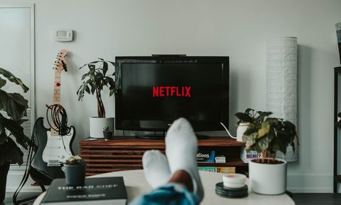 A person sitting in the living room with their feet up watching Netflix.