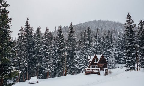 A snowy view with a cabin in the mountains .
