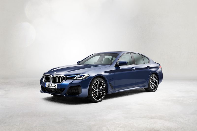 2021 BMW 5 Series front end angle from driver's side parked in a studio under bright lighting.