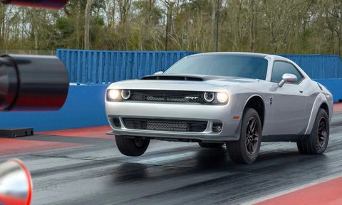 2023 Dodge Challenger SRT Demon 170 front end angle doing a wheelie on a drag strip in front of trees.