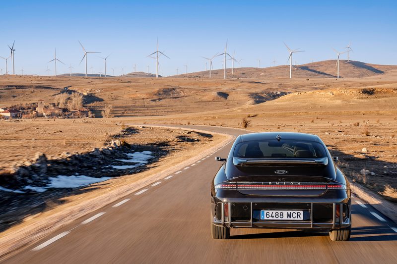 2023 Hyundai Ioniq 6 rear end close up driving down the road with windmills in the back.
