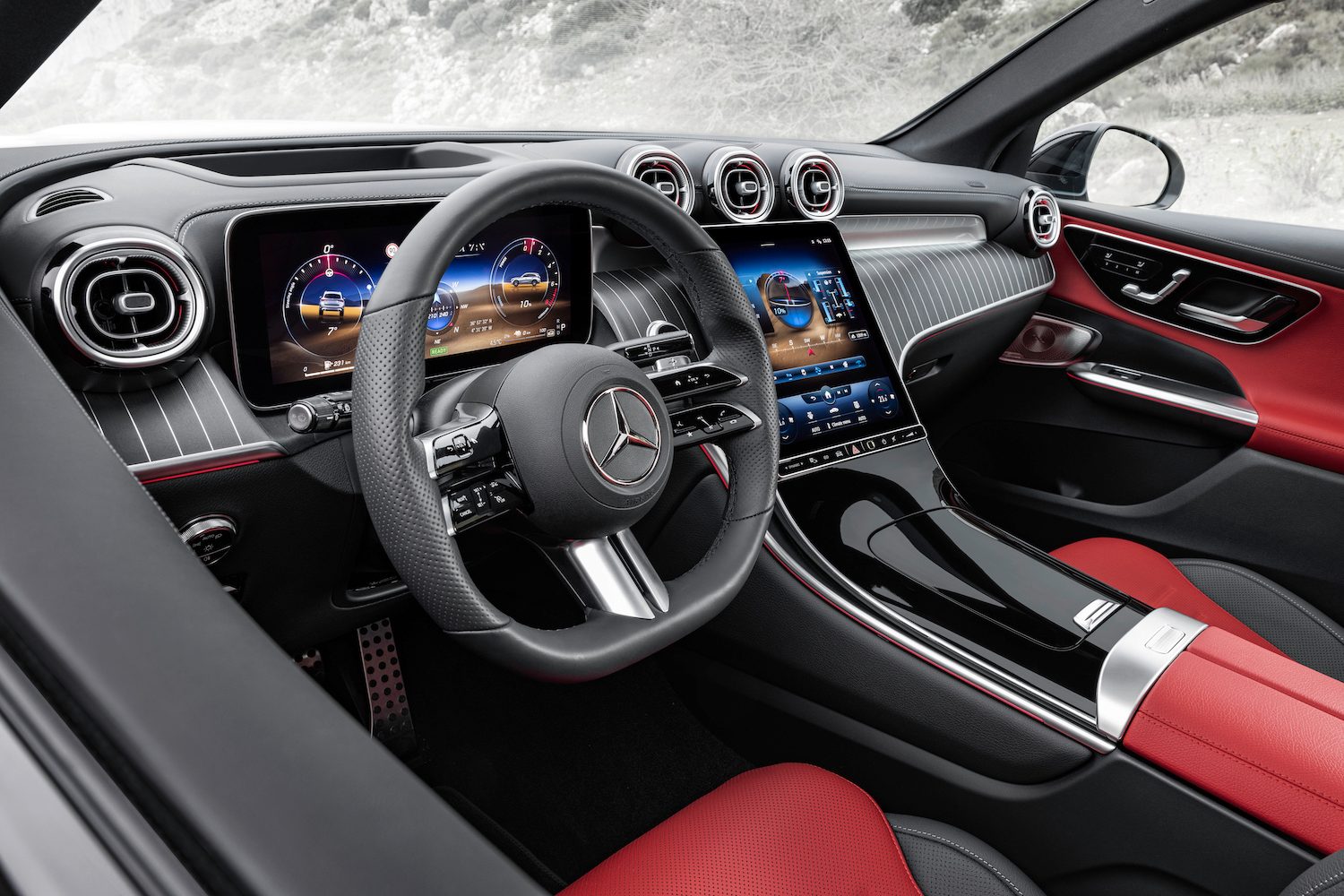 Close up of steering wheel in the 2023 Mercedes-Benz GLC from outside the driver's side in front of mountains.