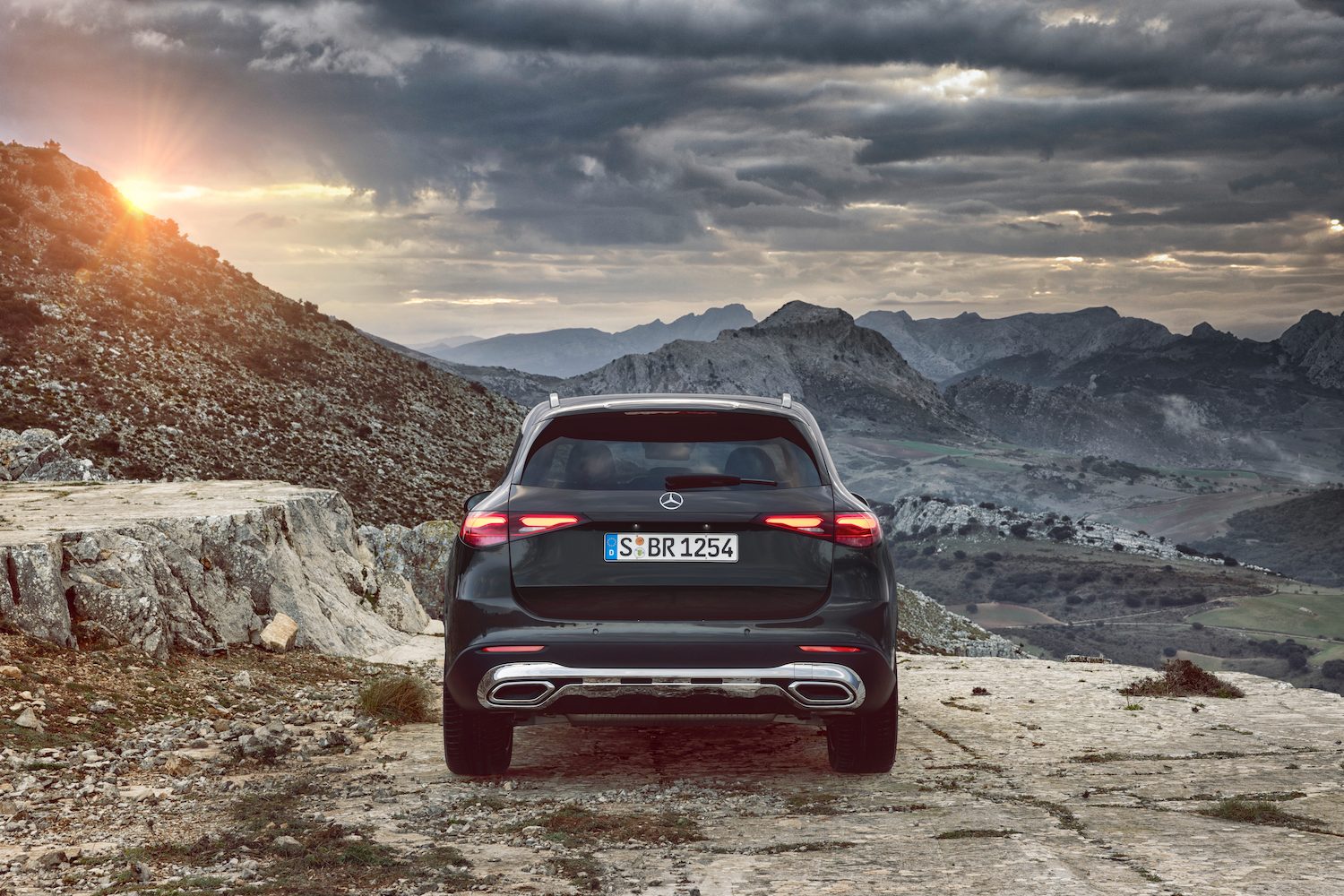 Rear end close up of the 2023 Mercedes-Benz GLC parked in front of mountains during sunset.
