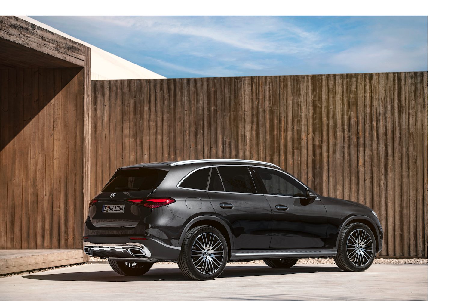 2023 Mercedes-Benz GLC rear end angle from the passenger's side parked in front of a tall wooden fence.