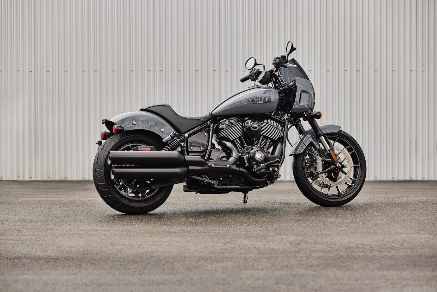 Rear end angle of the 2023 Indian Sport Chief parked in front of a wall parked on concrete.