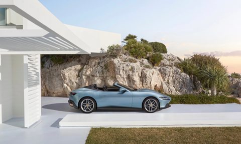2024 Ferrari Roma side profile with the roof down parked in front of a house with a cliff in the back.