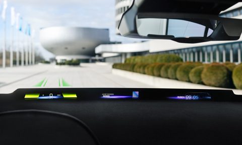 BMW Panoramic Vision in a rendering in a car driving down the road with futuristic buildings in the back.