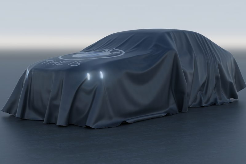BMW i5 electric sedan under a cover parked in a studio.