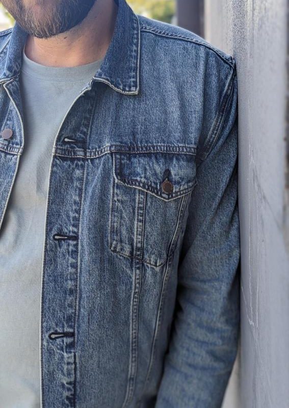 Man leaning on wall in denim trucker jacket