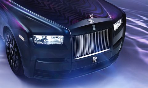 Close up of front end of the Rolls-Royce Phantom Syntopia from overhead with lights on and smoke in front of the car.