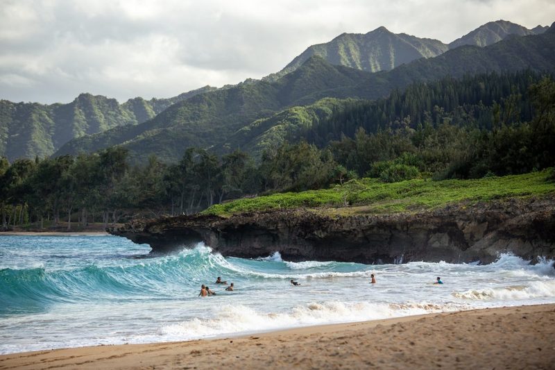 A shot of a beach in Hawaii with people in the water.