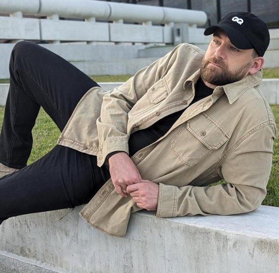 Man leaning in tan shacket and black denim