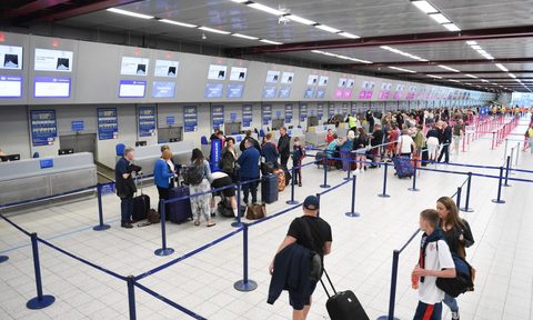 A busy airport with people getting in line at check in.