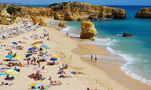 A shot of a beach with people relaxing and walking along the shore.