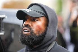 Kanye West wearing a hoodie and a hat