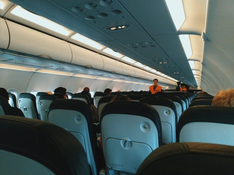 The inside of a plane with the passengers seated.