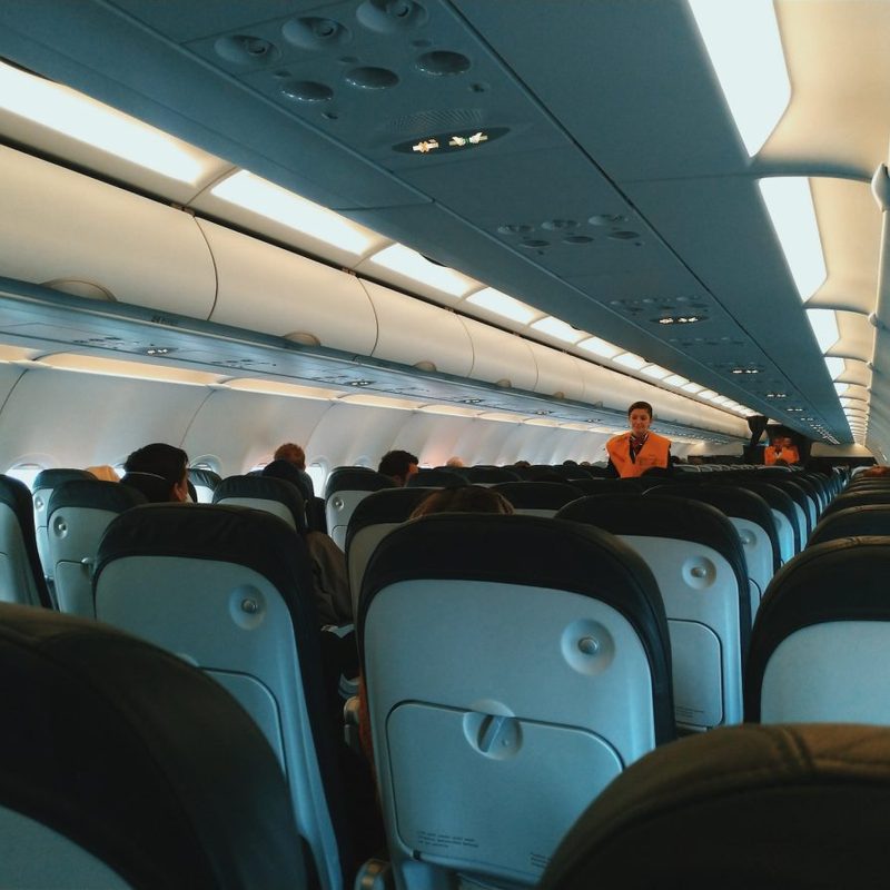 The inside of a plane with the passengers seated.
