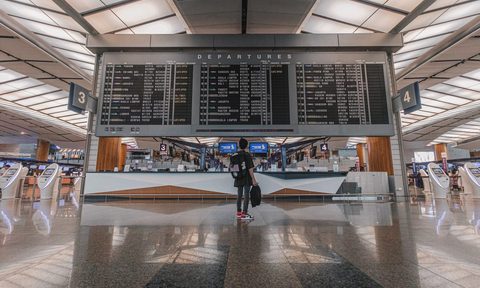 Person checking for their flight on the flight departure board at the airport.