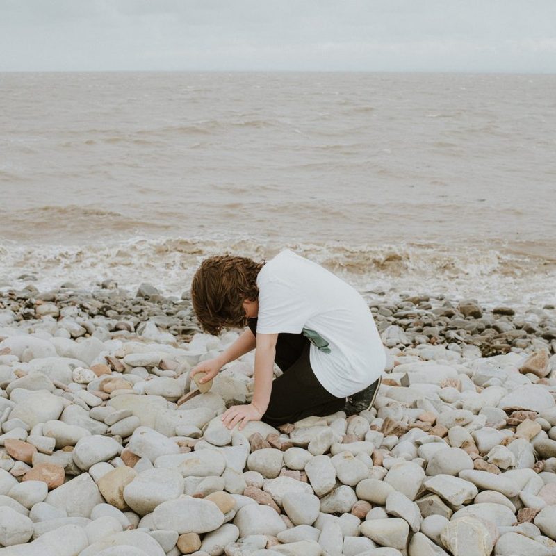 A person digging in the rocks on the beach
